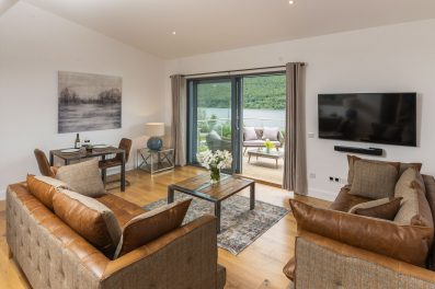 open plan living space with brown leather sofas and view of loch