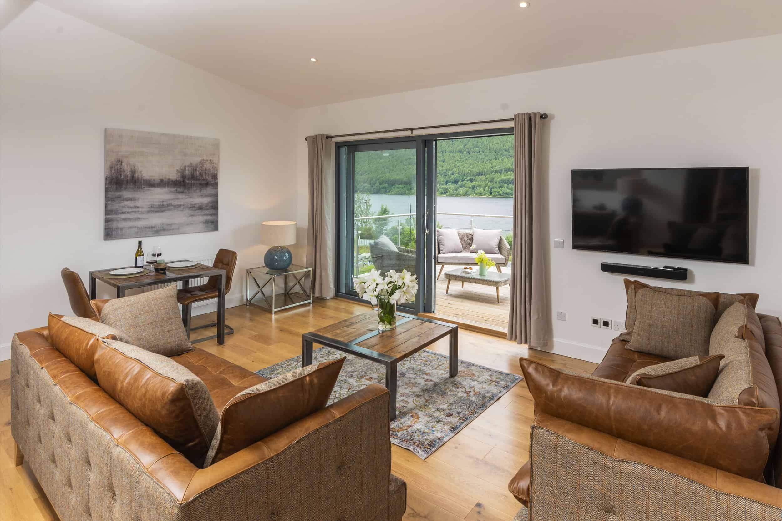 open plan living space with brown leather sofas and view of loch